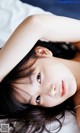 A woman laying on top of a bed with her hands behind her head.