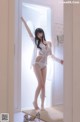 A woman in a white lingerie standing in a doorway.