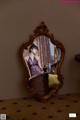 A woman sitting in front of a mirror in a room.